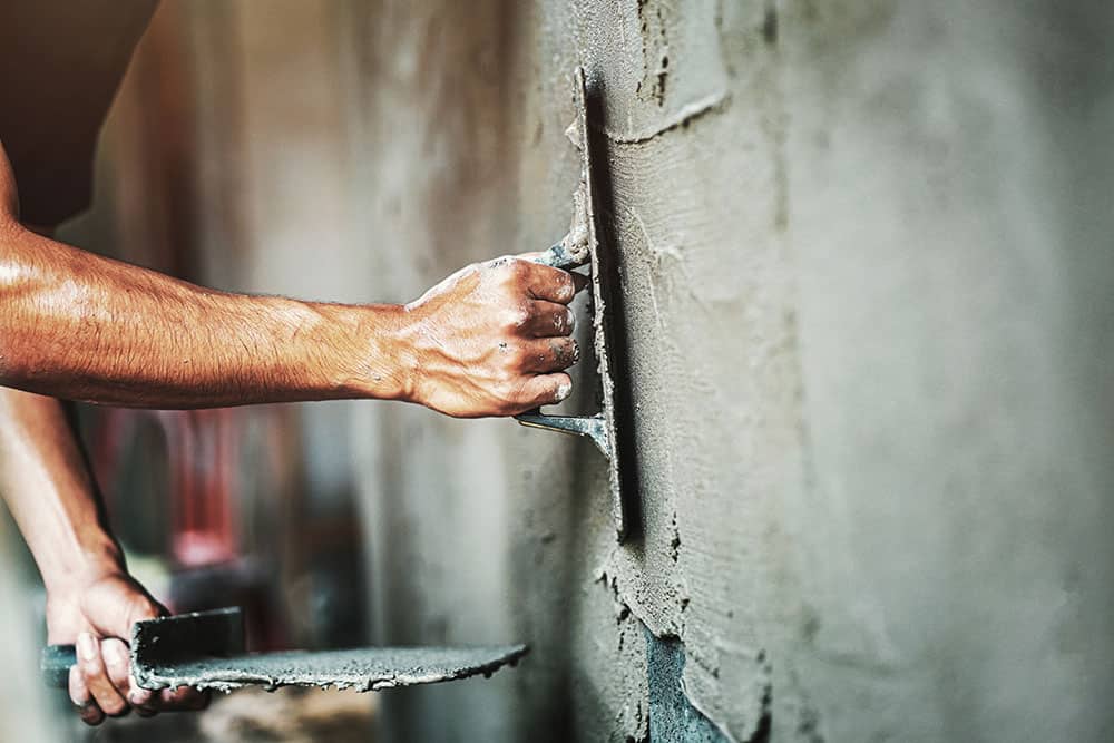 closeup hand of worker plastering cement at wall for building ho